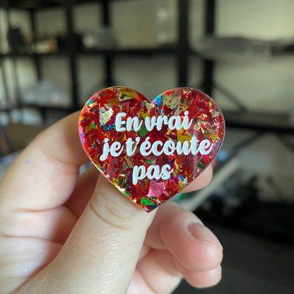 Broche "En vrai je t'écoute pas" en acrylique transparente avec des éclats de confettis rouges et multicolores