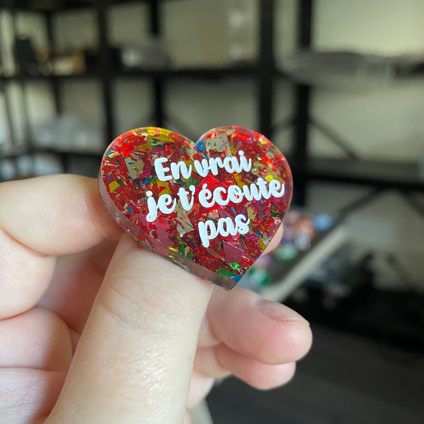 Broche "En vrai je t'écoute pas" en acrylique transparente avec des éclats de confettis rouges et multicolores