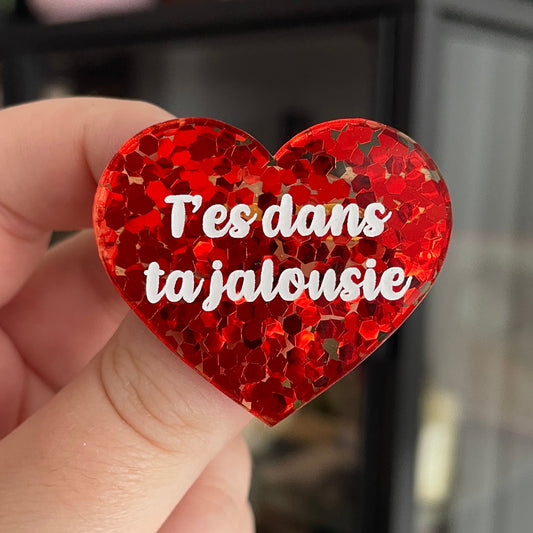 Broche "T'es dans ta jalousie" en acrylique semi transparente avec des confettis rouges