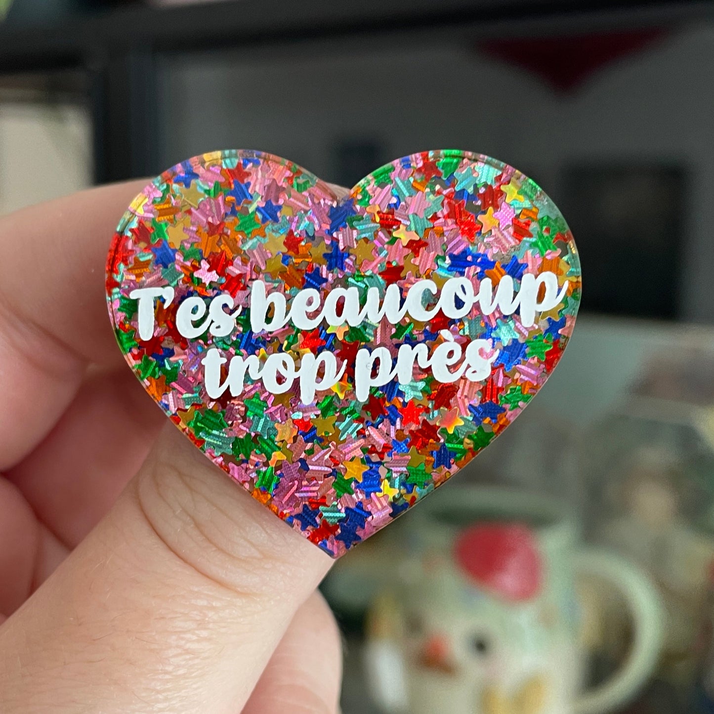 Broche "T'es beaucoup trop près" en acrylique avec des confettis étoiles multicolores
