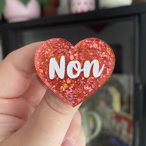 Broche "Non" en acrylique à paillettes oranges/corail