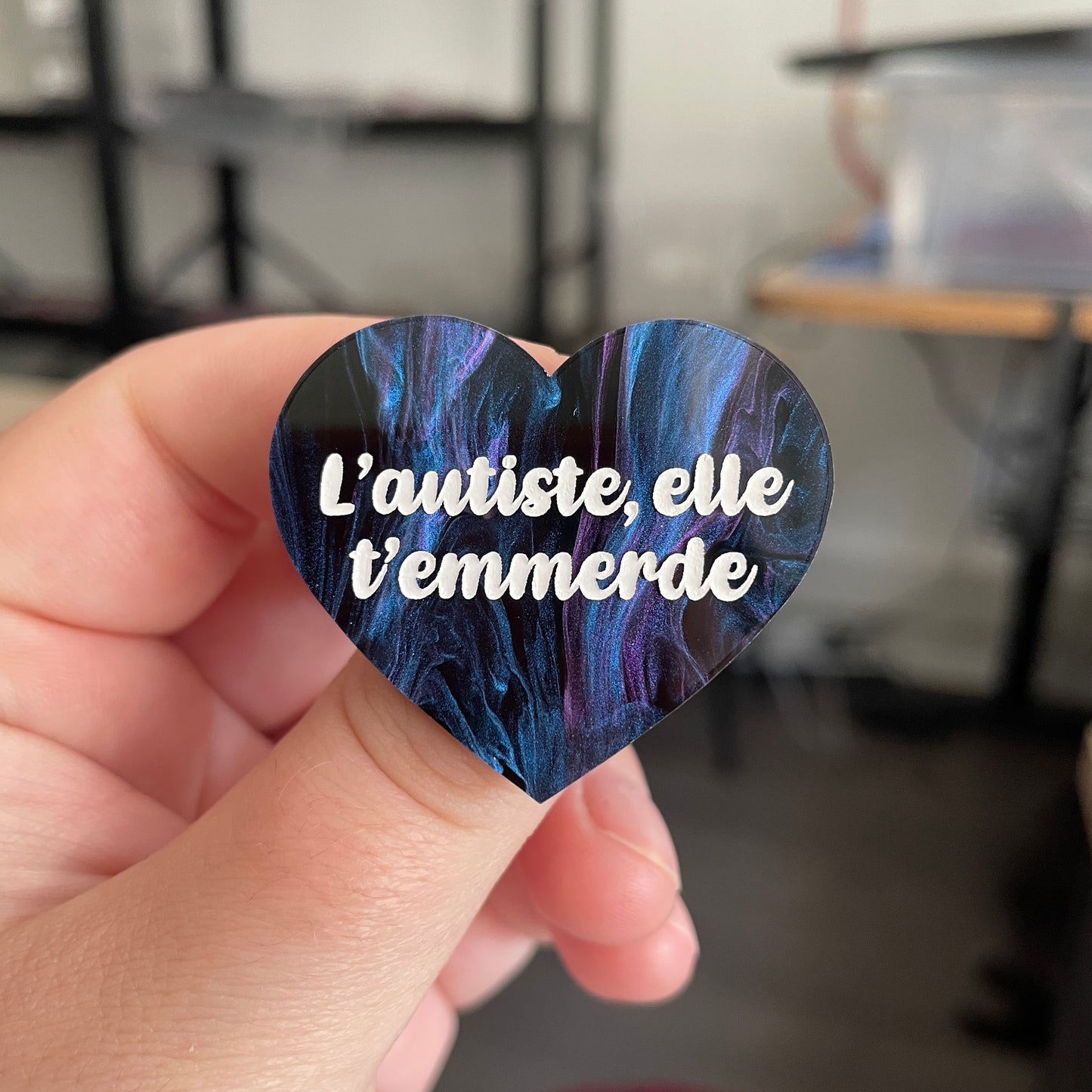 Broche "L'autiste, elle t'emmerde" en acrylique marbrée noire, bleue et violette (à dominante bleue)