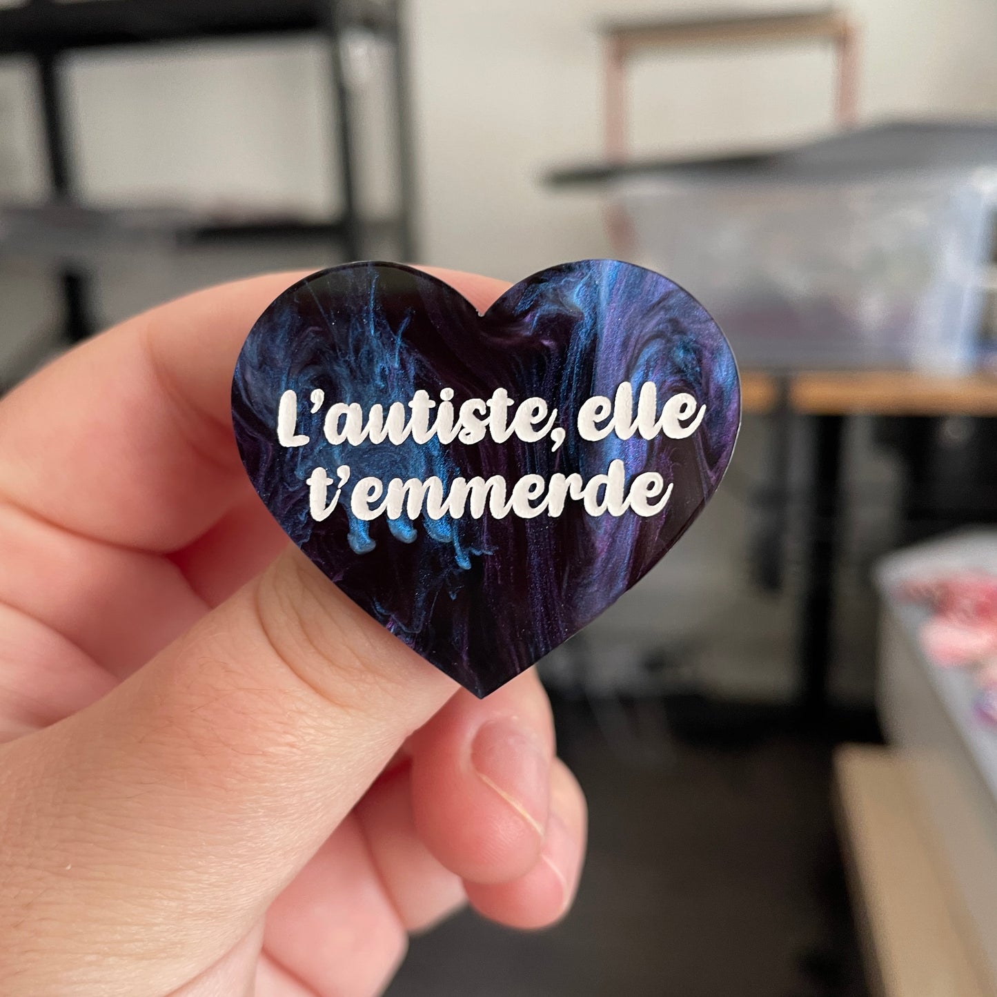 Broche "L'autiste, elle t'emmerde" en acrylique marbrée noire, bleue et violette (à dominante noire)