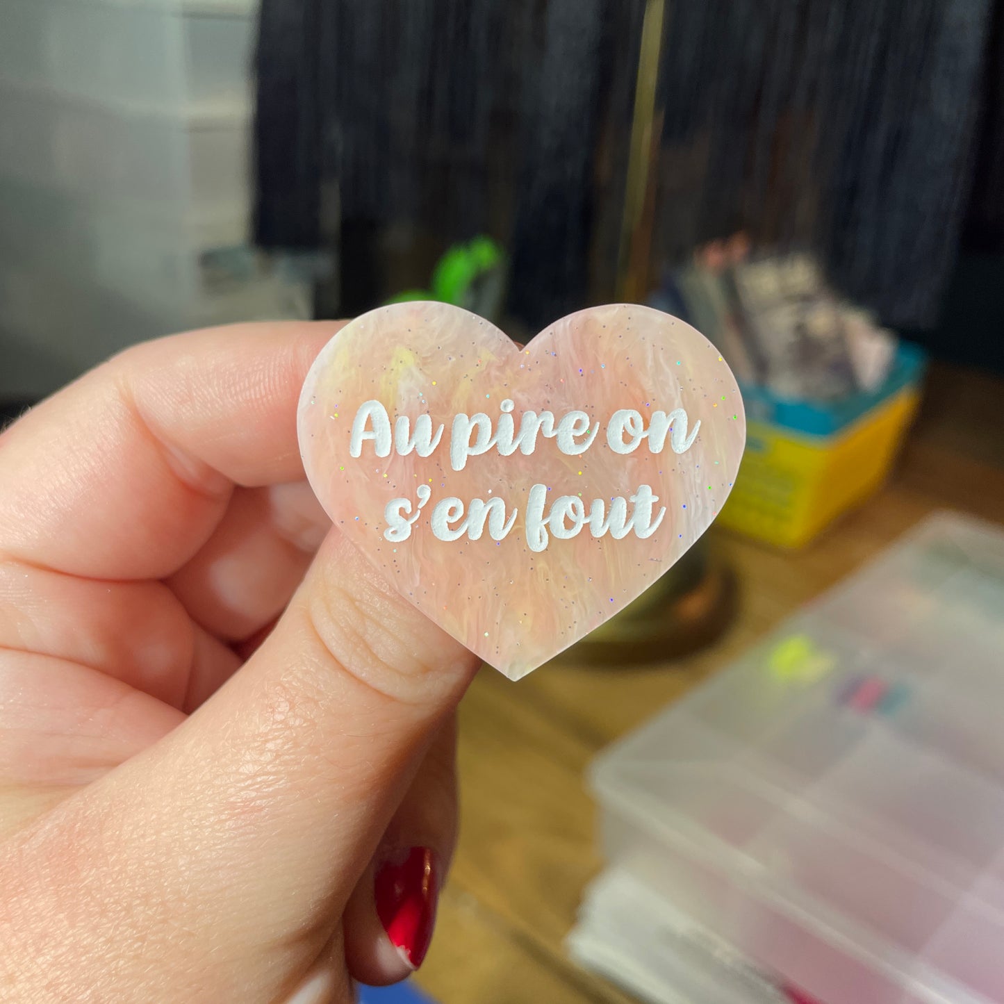 Broche "Au pire on s'en fout" en acrylique semi transparente marbrée corail, orange et jaune à paillettes