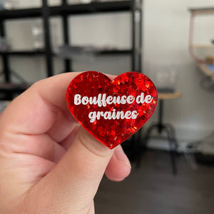 Broche "Bouffeuse de graines" en acrylique semi transparente avec des confettis rouges