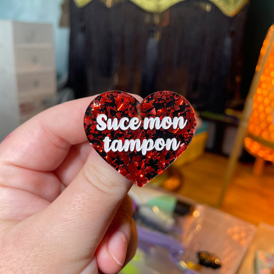 Broche "Suce mon tampon" en acrylique noire avec des éclats de confettis rouges