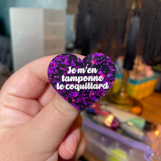 Broche "Je m'en tamponne le coquillard" en acrylique noire avec des éclats de confettis violets