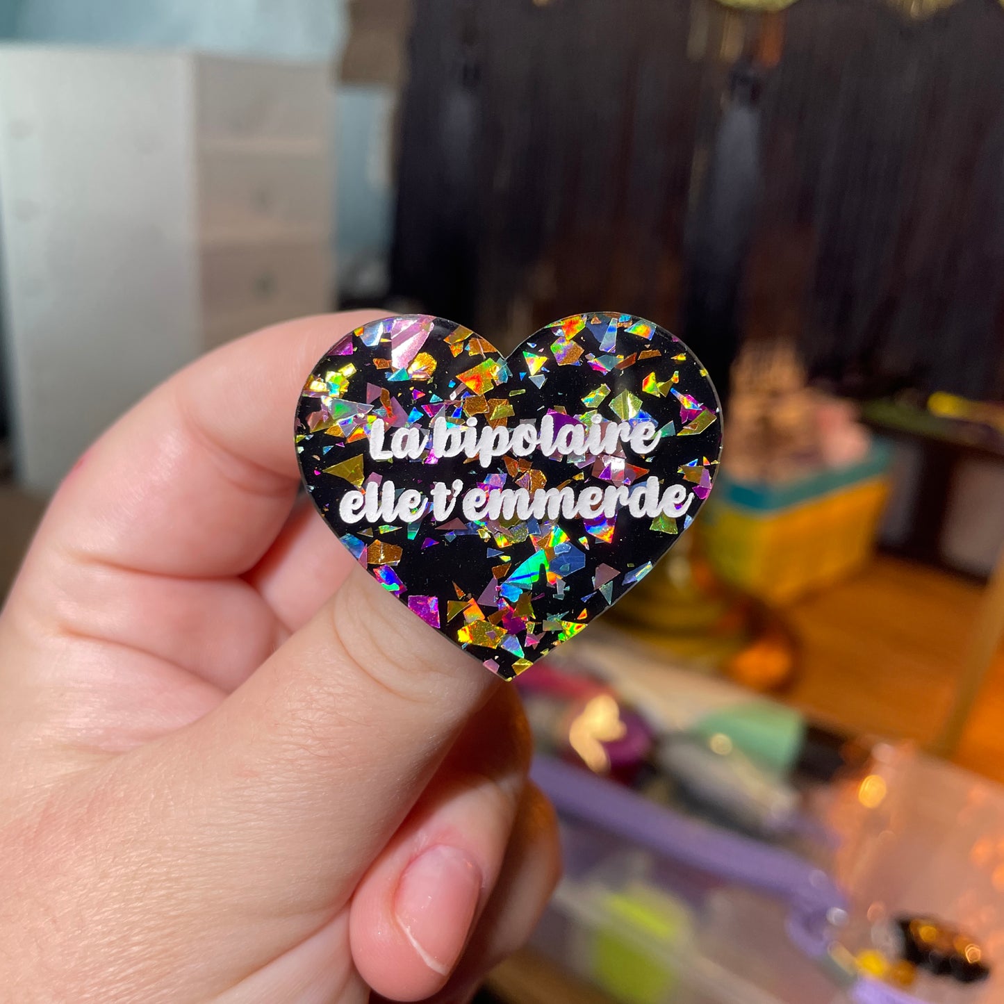 Broche "La bipolaire elle t'emmerde" en acrylique noire avec des éclats de confettis multicolores