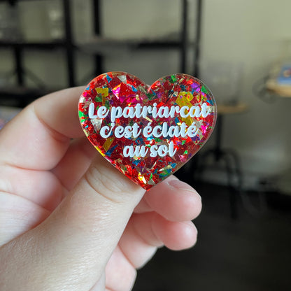 [CONTRÔLE TECHNIQUE] Broche "Le patriarcat c'est éclaté au sol" en acrylique transparente avec des éclats de confettis rouges et multicolores