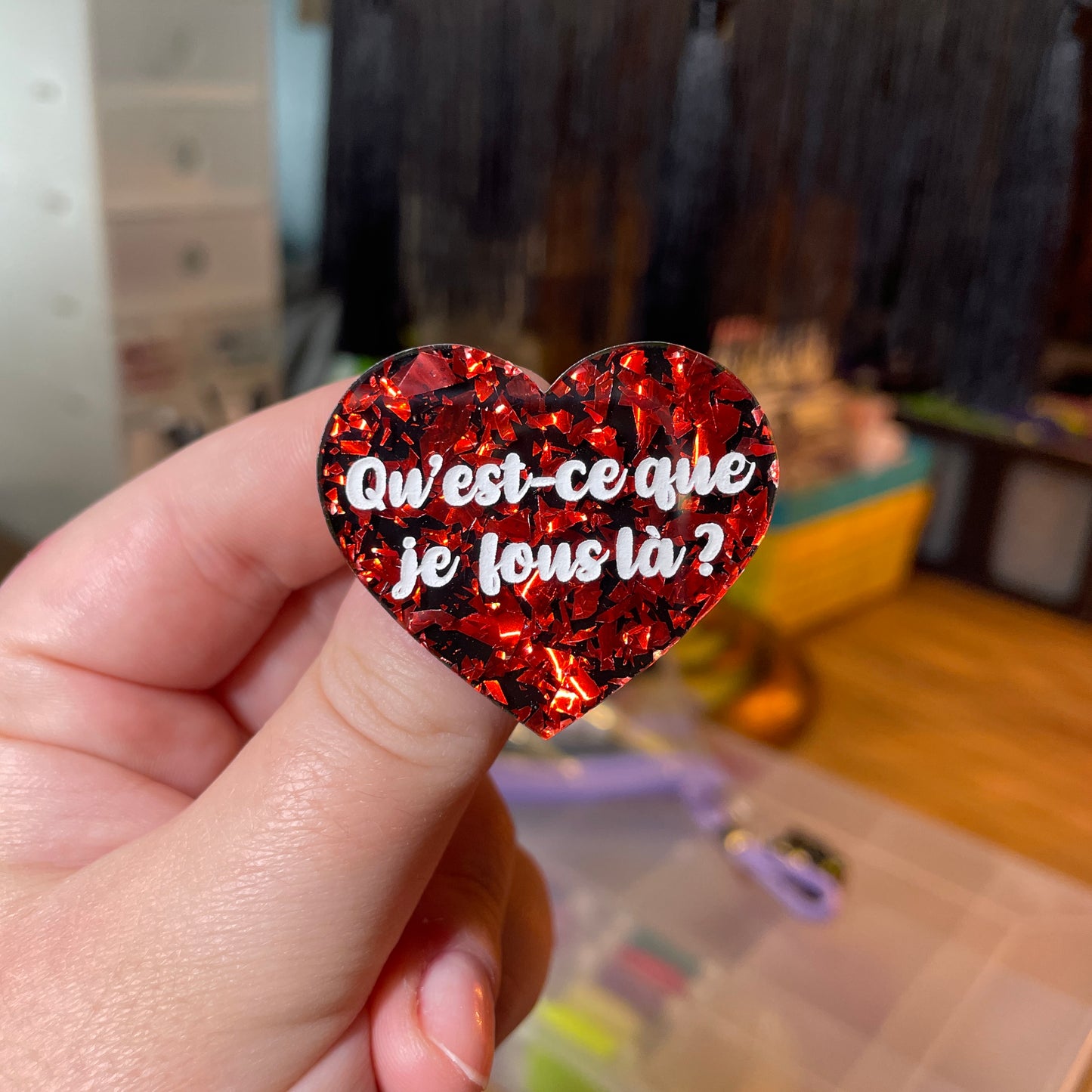 [Contrôle technique] Broche "Qu'est-ce que je fous là ?" en acrylique noire avec des éclats de confettis rouges
