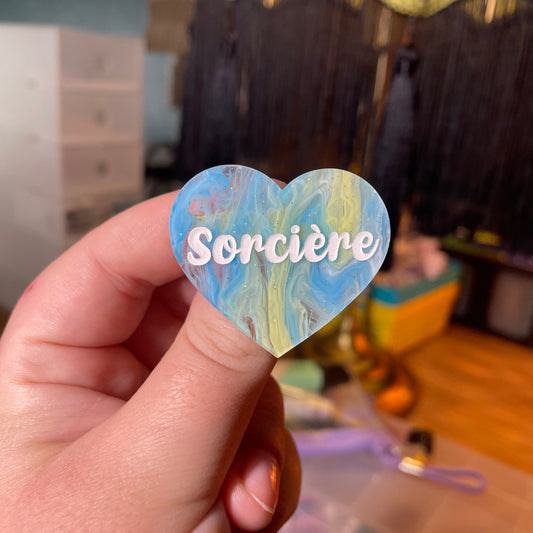 [Contrôle technique] Broche "Sorcière" en acrylique semi transparente marbrée bleue, blanche et jaune à paillettes