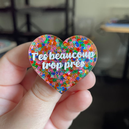 [CONTRÔLE TECHNIQUE] Broche "T'es beaucoup trop près" en acrylique semi transparente avec des confettis étoiles multicolores