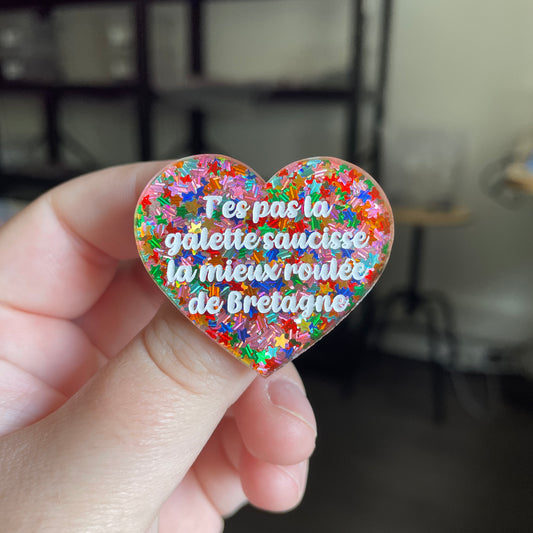 [CONTRÔLE TECHNIQUE] Broche "T'es pas la galette saucisse la mieux roulée de Bretagne" en acrylique semi transparente avec des confettis étoiles multicolores