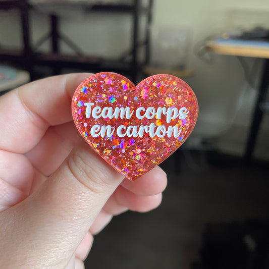 [CONTRÔLE TECHNIQUE] Broche "Team corps en carton" en acrylique semi transparente avec des paillettes corail