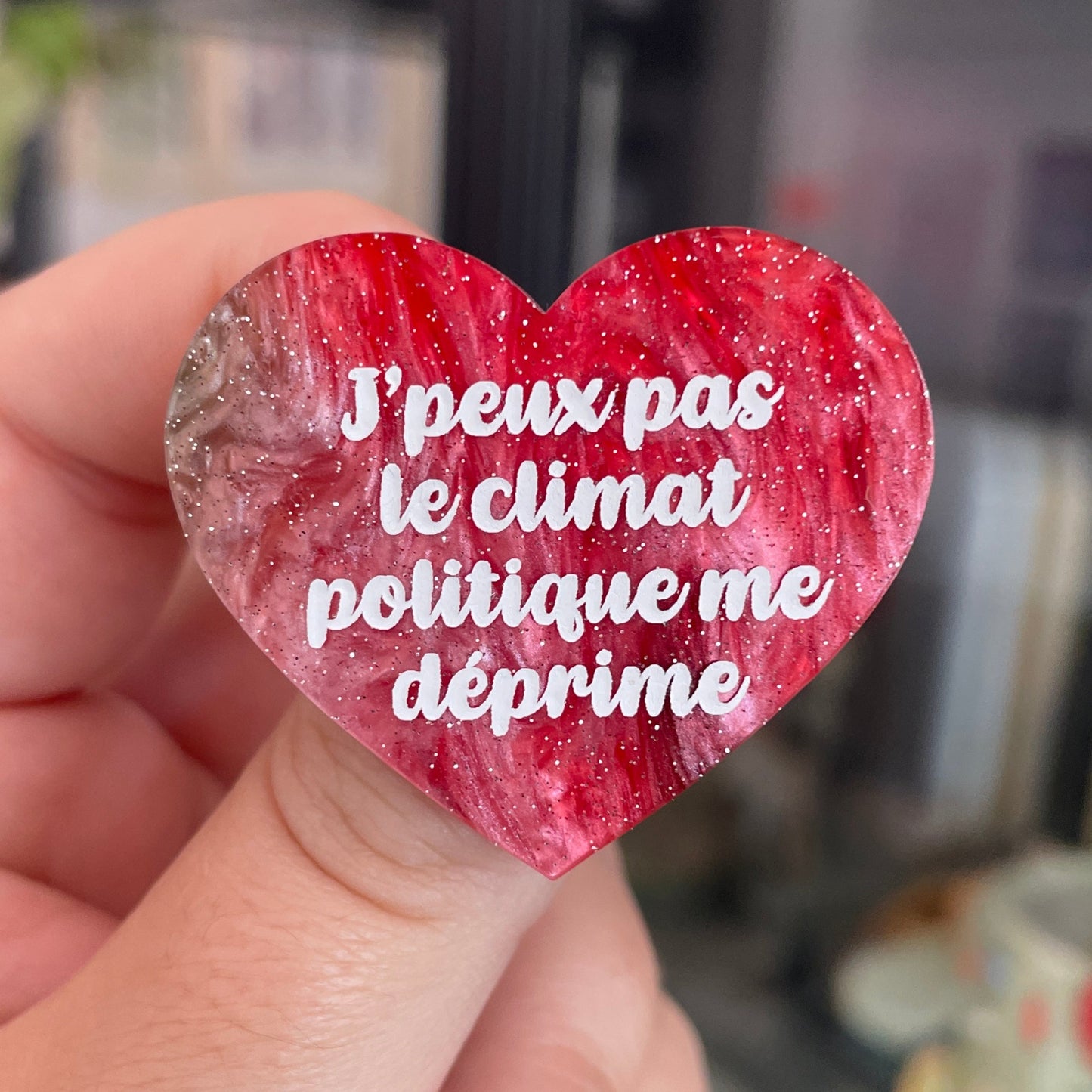 Broche "J'peux pas le climat politique me déprime" en acrylique marbrée rouge, marron, verte et blanche