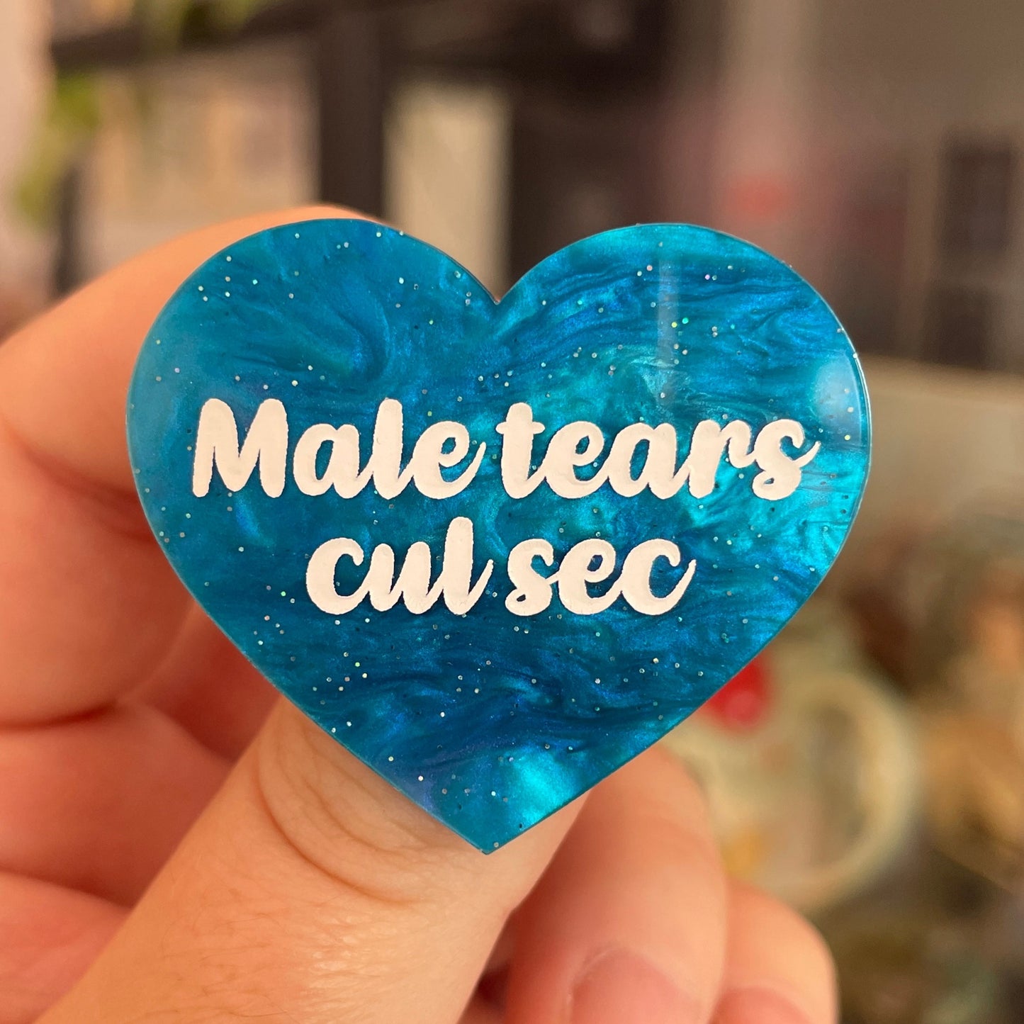 Broche "Male tears cul sec" en acrylique marbrée bleue à paillettes