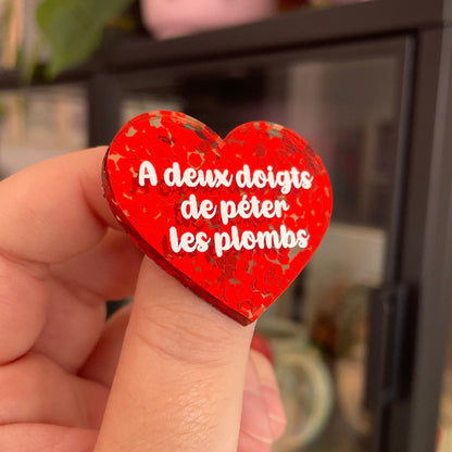 Broche "A deux doigts de péter les plombs" en acrylique semi-transparente avec des confettis rouges