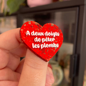 Broche "A deux doigts de péter les plombs" en acrylique semi-transparente avec des confettis rouges