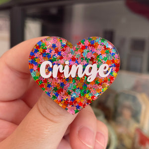 Broche "Cringe" en acrylique semi-transparente avec des confettis étoiles multicolores