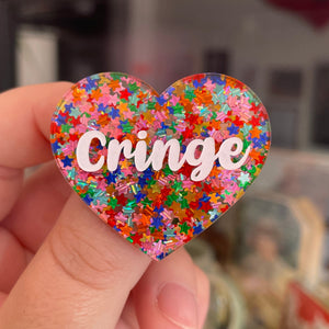 Broche "Cringe" en acrylique semi-transparente avec des confettis étoiles multicolores