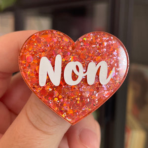 Broche "Non" en acrylique à paillettes oranges/corail