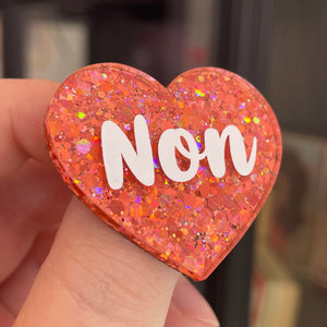 Broche "Non" en acrylique à paillettes oranges/corail