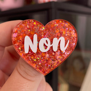 Broche "Non" en acrylique à paillettes oranges/corail