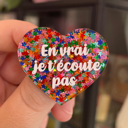 Broche "En vrai je t'écoute pas" en acrylique semi-transparente avec des confettis étoiles multicolores