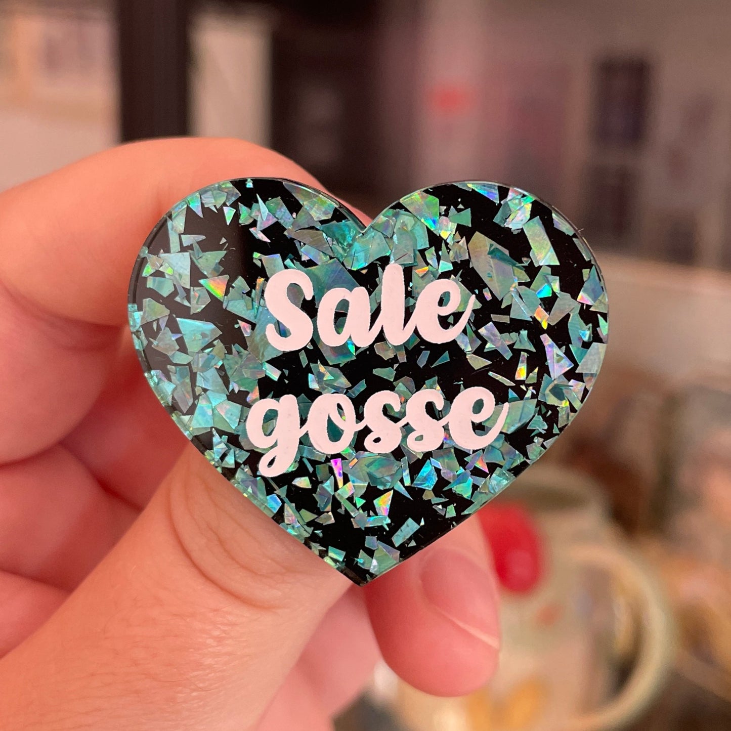 Broche "Sale gosse" en acrylique noire avec des éclats de confettis turquoise