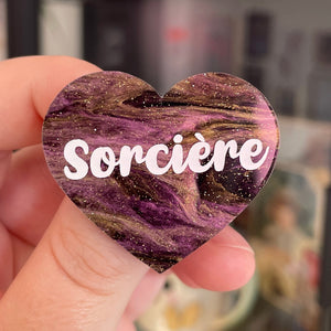 Broche "Sorcière" en acrylique marbrée noire, dorée et violette à paillettes