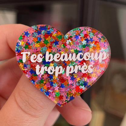 Broche "T'es beaucoup trop près" en acrylique semi-transparente avec des confettis étoiles multicolores