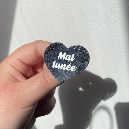 Broche "Mal lunée" en acrylique à paillettes noires holographiques