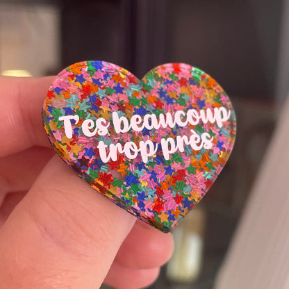 [CONTRÔLE TECHNIQUE] Broche "T'es beaucoup trop près" en acrylique semi-transparente avec des confettis étoiles multicolores