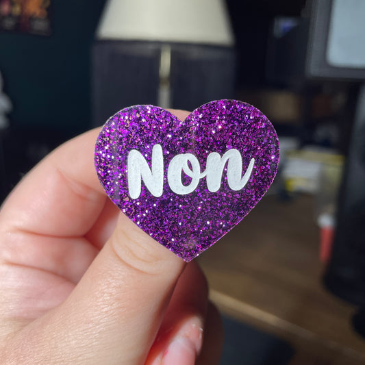 Broche "Non" en acrylique à paillettes violettes