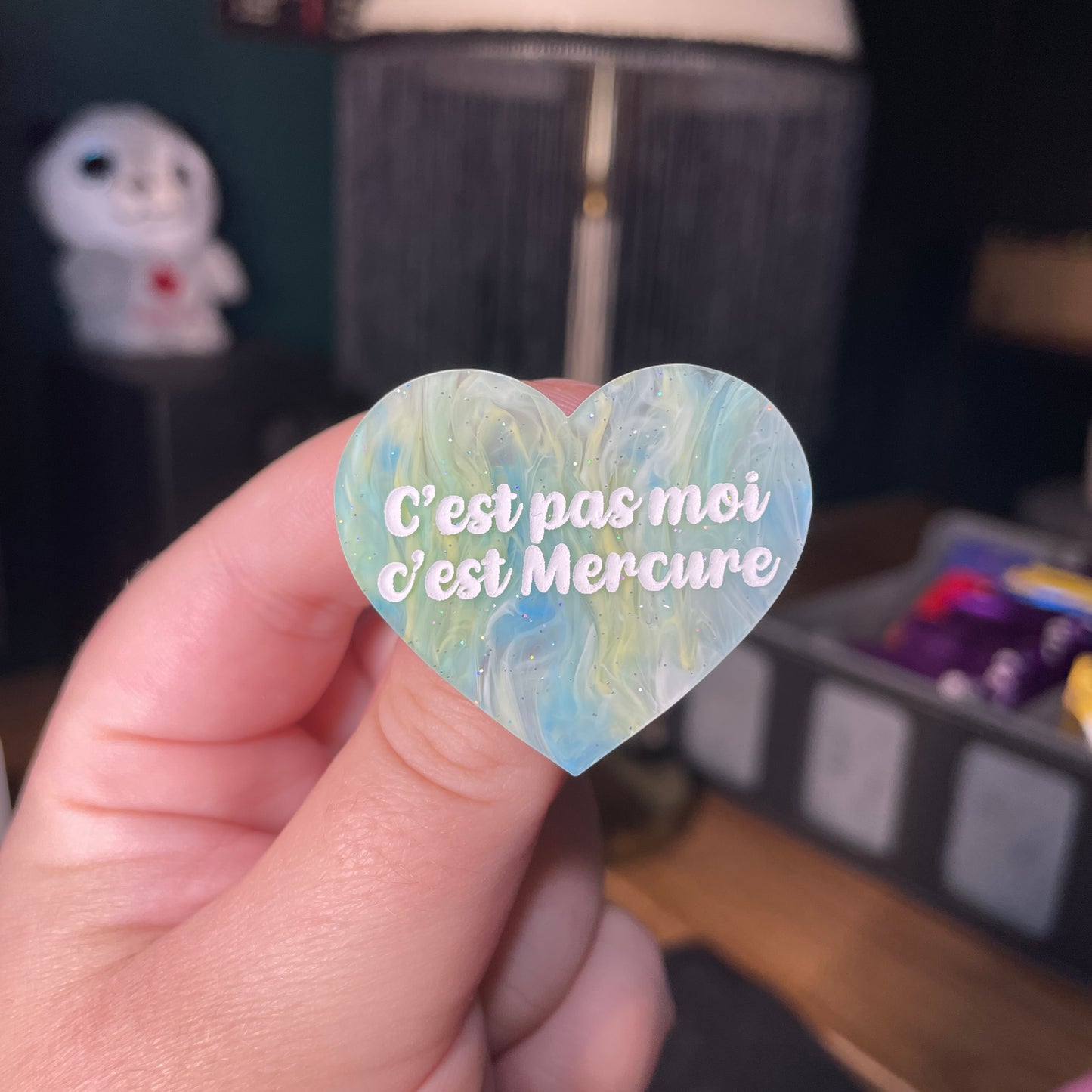 Broche "C'est pas moi c'est Mercure" en acrylique semi transparente marbrée bleue et jaune à paillettes