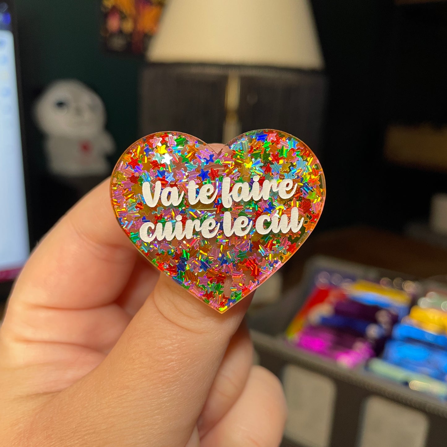 Broche "Va te faire cuire le cul" en acrylique semi transparente avec des étoiles multicolores