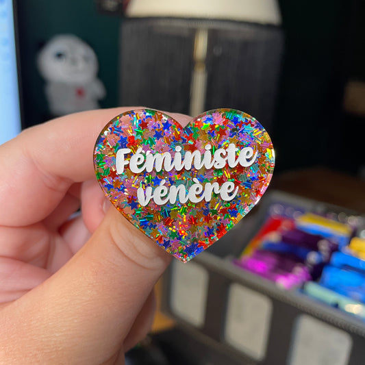 Broche "Féministe vénère" en acrylique semi transparente avec des étoiles multicolores