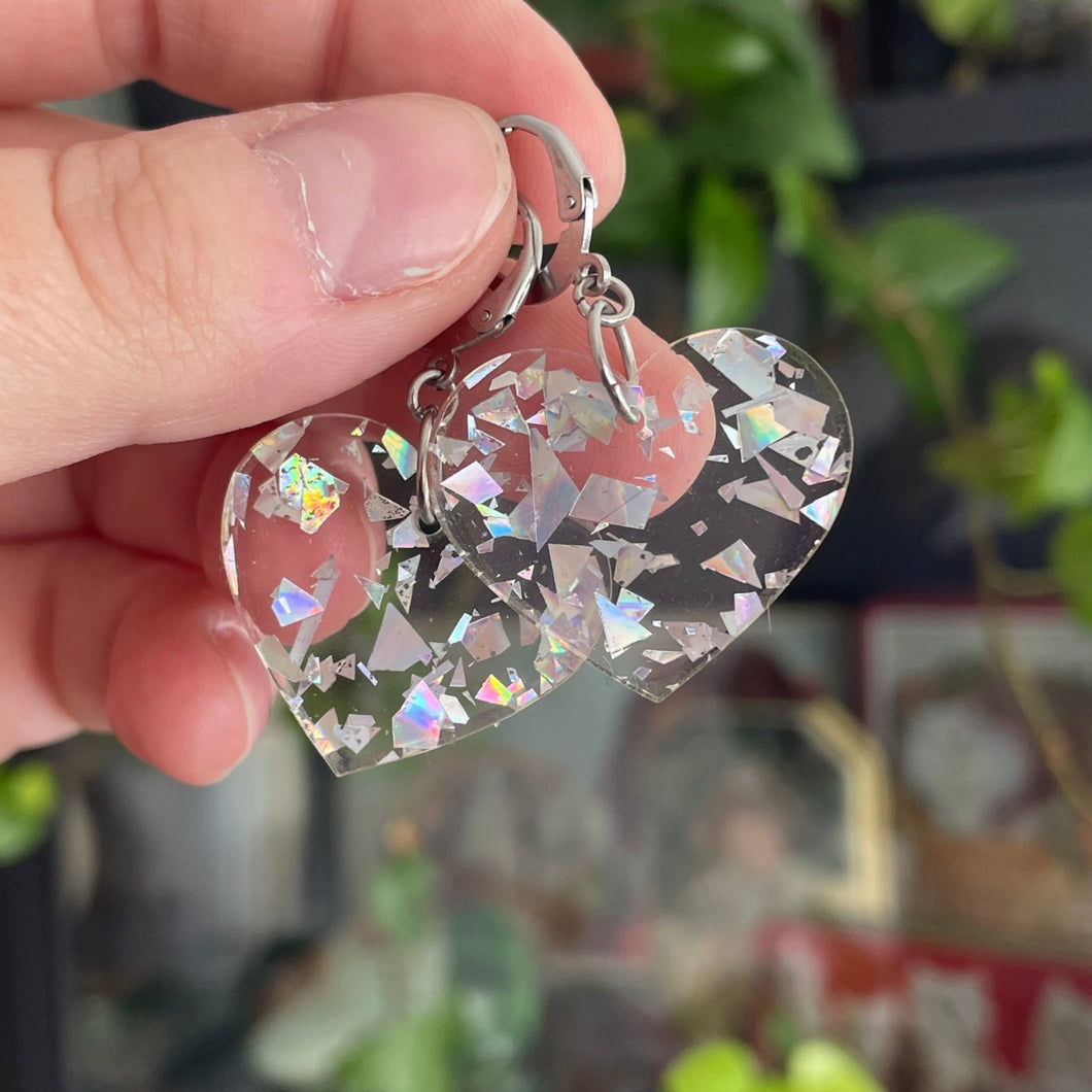 Petites boucles d'oreilles coeurs pendantes en acrylique transparente avec des éclats de confettis argentés