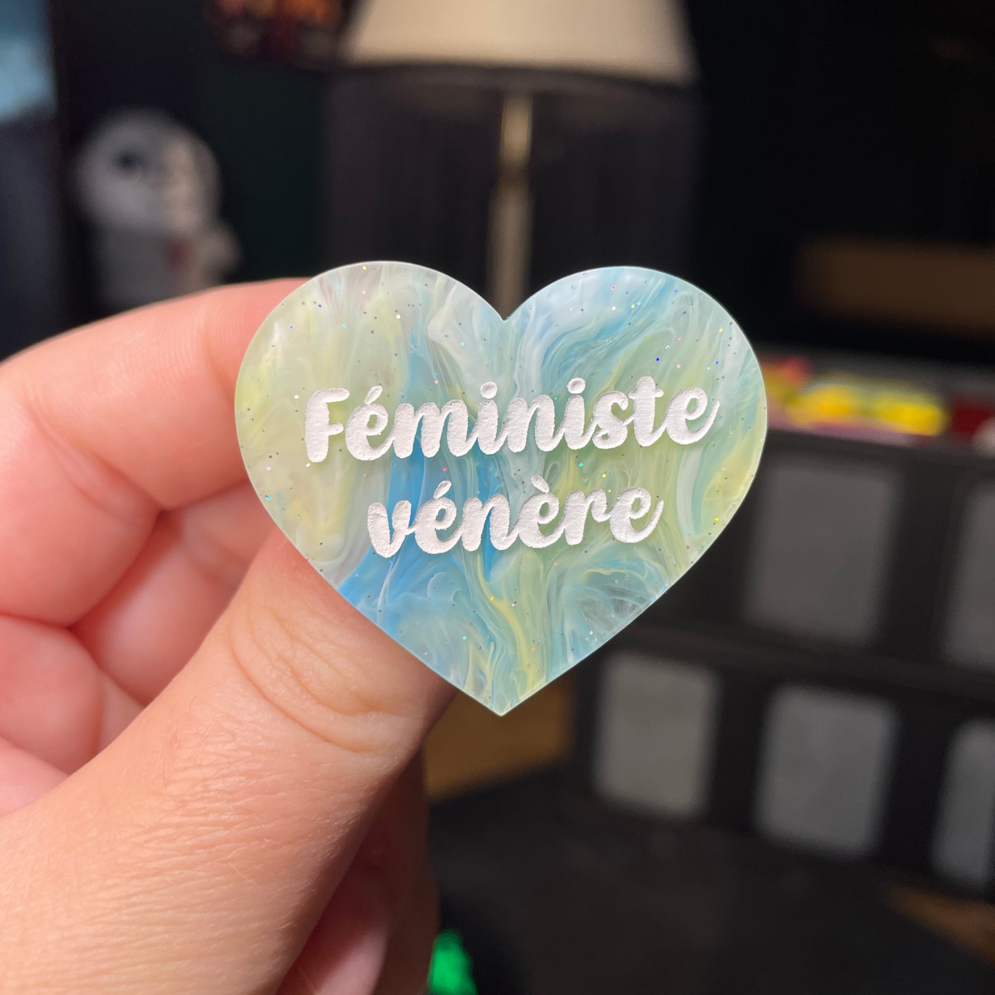 Broche "Féministe vénère" en acrylique semi transparente marbrée bleue et jaune à paillettes