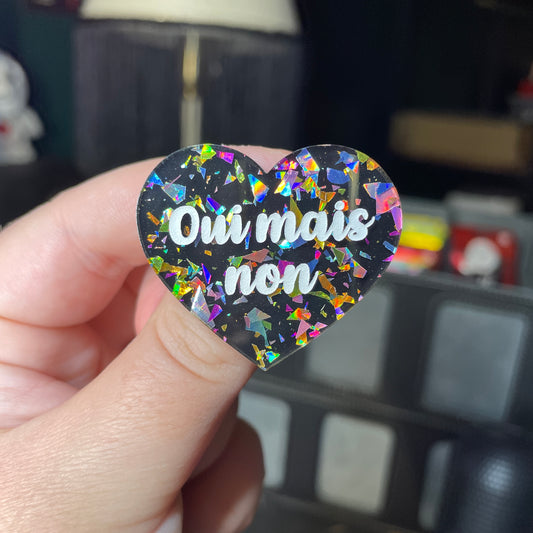 Broche "Oui mais non" en acrylique noire avec des éclats de confettis multicolores