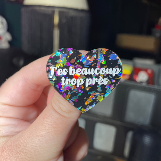 Broche "T'es beaucoup trop près" en acrylique noire avec des éclats de confettis multicolores