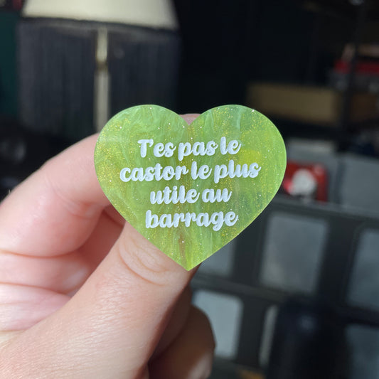 Broche "T'es pas le castor le plus utile au barrage" en acrylique semi transparente marbrée verte et dorée à paillettes