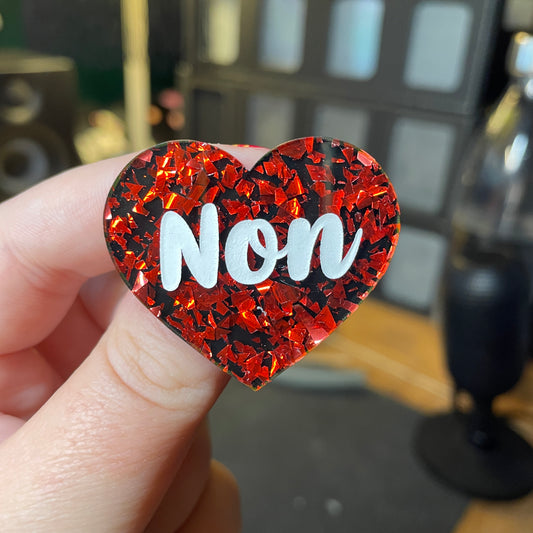 [Contrôle technique] Broche "Non" en acrylique noire avec des éclats de confettis rouges