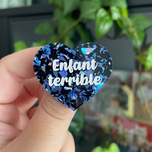 [CONTRÔLE TECHNIQUE] Broche "Enfant terrible" en acrylique noire avec des éclats de confettis bleus