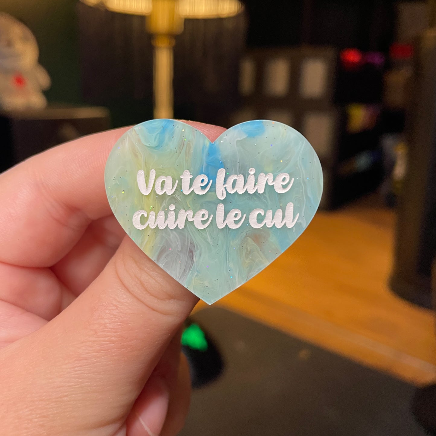 [Contrôle technique] Broche "Va te faire cuire le cul" en acrylique semi transparente marbrée bleue, jaune et blanche à paillettes