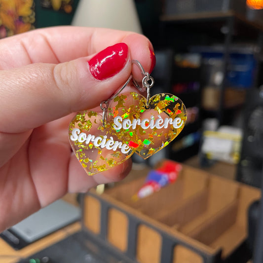 Paire de boucles d'oreilles "Sorcière" en acrylique transparente avec des éclats de confettis dorés