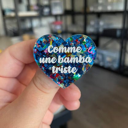 [CONTRÔLE TECHNIQUE] Broche "Comme une bamba triste" en acrylique transparente avec des éclats de confettis bleus et multicolores