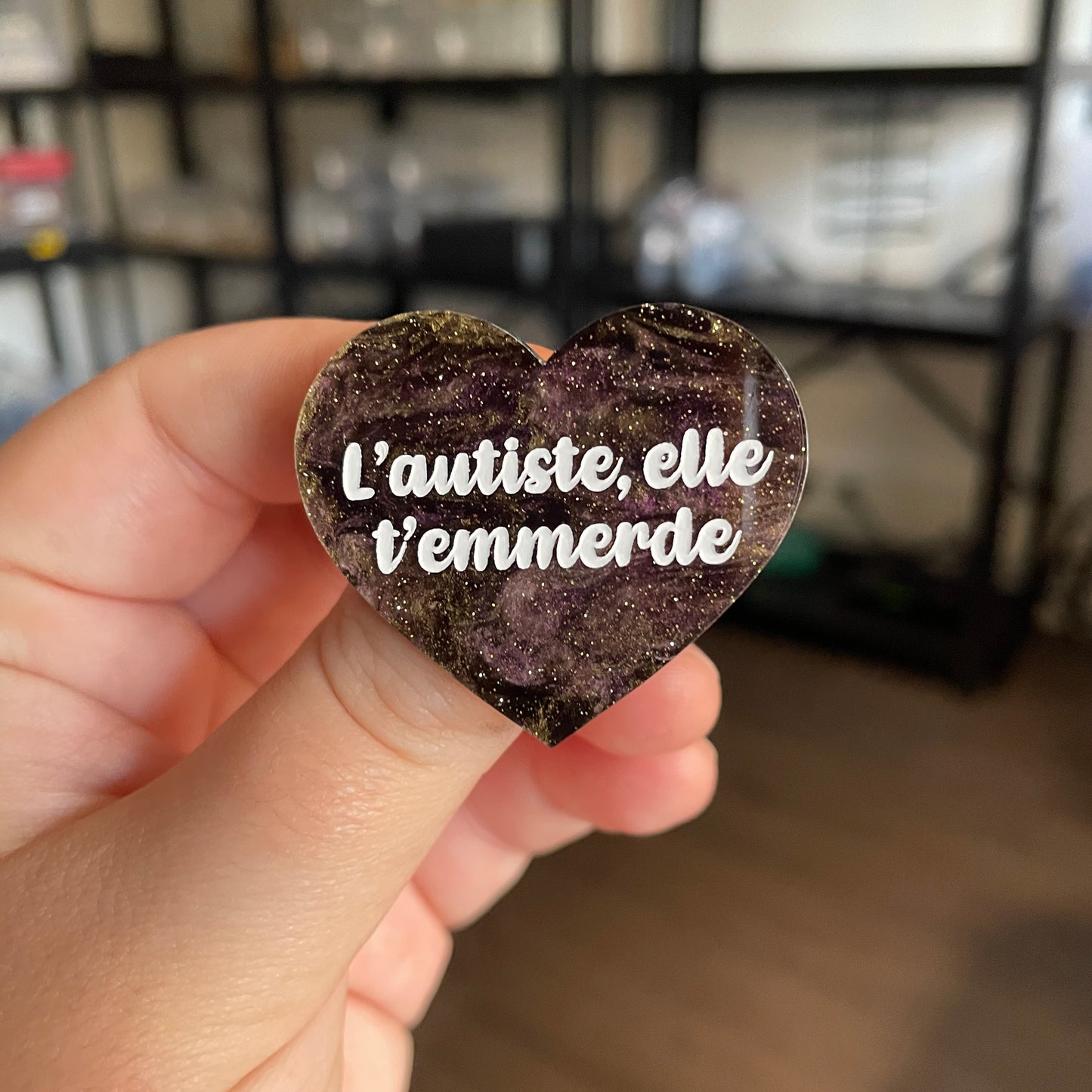 [CONTRÔLE TECHNIQUE] Broche "L'autiste, elle t'emmerde" en acrylique marbrée noire, violette et dorée à paillettes