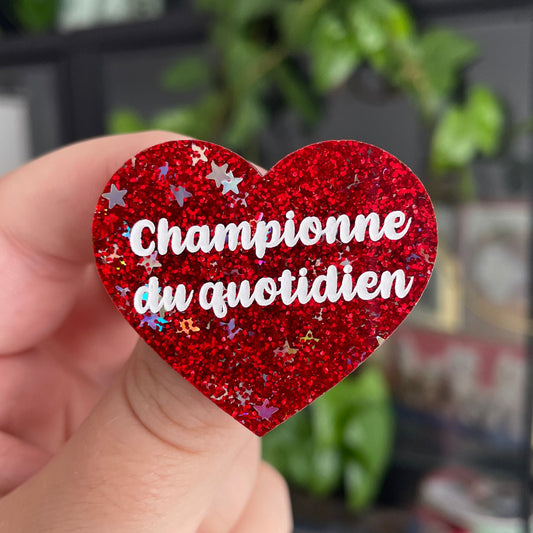 Broche "Championne du quotidien" en acrylique à paillettes rouges et étoiles iridescentes