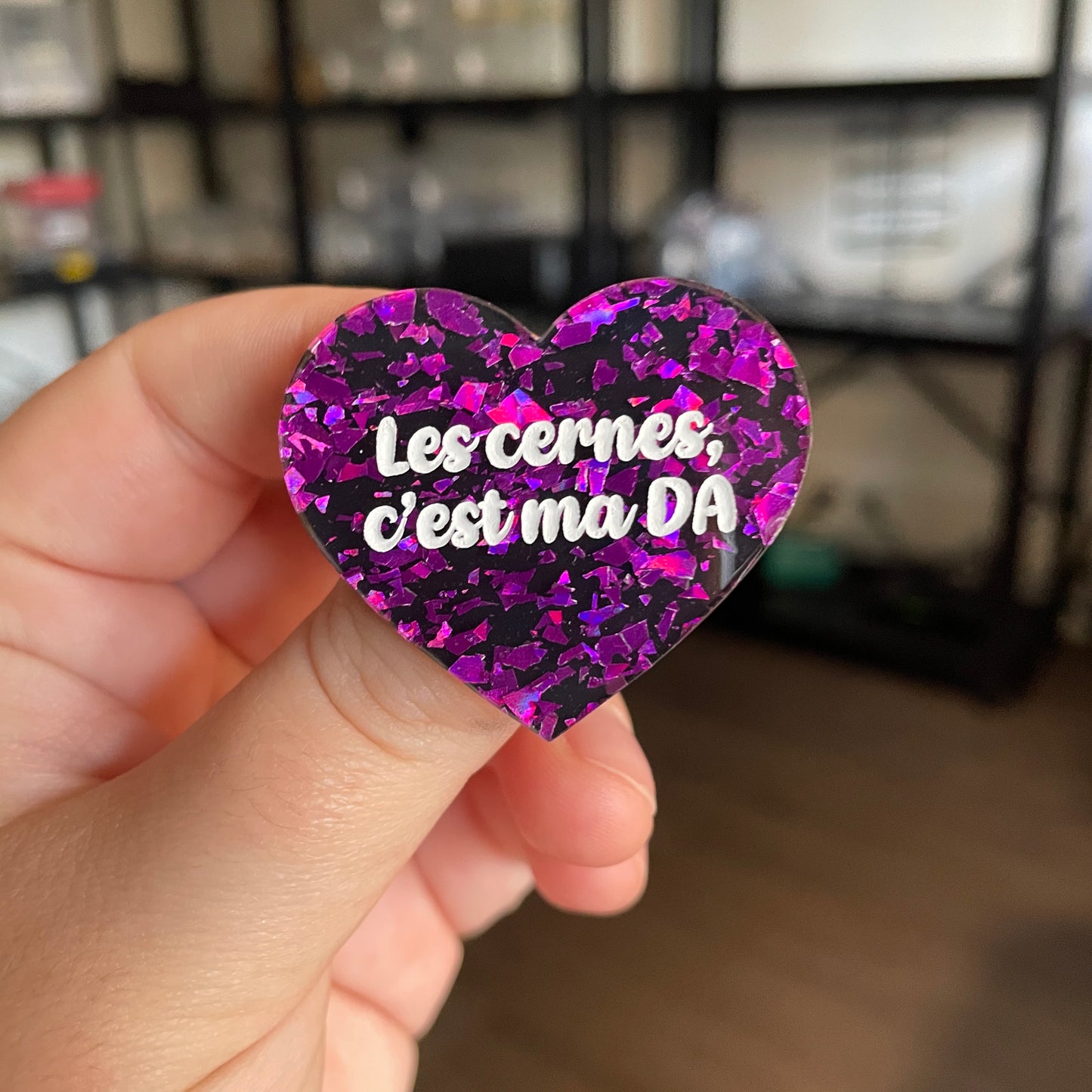 [CONTRÔLE TECHNIQUE] Broche "Les cernes, c'est ma DA" en acrylique noire avec des éclats de confettis violets